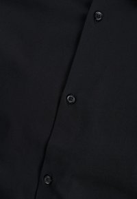 Zwarte knoopjesoverhemd met gladde stof, voorzien van drie zwarte knopen langs de knoopsluiting en een klassiek kraagontwerp.