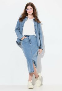 Vaaleansininen farkkuhame ja -takki -setti, jossa on edessä halkio, yhdistettynä valkoiseen t-paitaan ja kermaisia lenkkareita. Käytössä kirkkaat lasit.