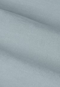 Tissu bleu clair avec un fin motif de tissage diagonal et des plis doux créant des ombres délicates.