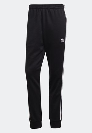 Pantalon de survêtement Adidas noir avec taille élastique, bandes latérales blanches, poignets côtelés et logo Trefoil Adidas sur la cuisse gauche.