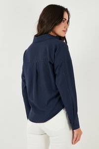 Navy blue long-sleeve shirt with a relaxed fit, featuring a back yoke and slightly rounded hem; made of smooth fabric with button cuffs.