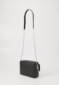 Borsa in pelle nera di forma rettangolare, dotata di una tracolla a catena staccabile e una superficie liscia. Chiusura con cerniera nella parte superiore.