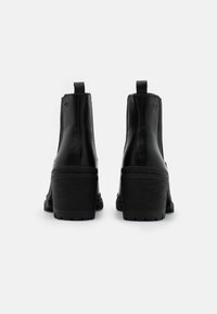 Černé kožené kotníkové boty na blokovém podpatku, s elastickými postranními panely, zadními poutky a texturovanou gumovou podrážkou. Čistý, minimalistický design.