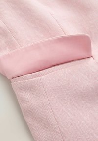 Tissu à chevrons rose clair avec un détail de revers plié montrant une doublure rose uni et lisse.