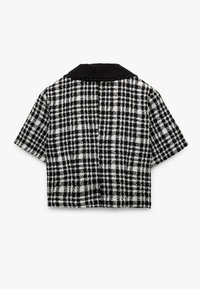 Verkorte blouse in een zwart-wit houndstooth patroon, met een zwarte kraag en korte mouwen, gemaakt van gestructureerde stof.