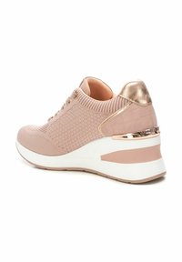 Zapatilla de color rosa claro con un tejido de punto texturizado, detalles metálicos y una gruesa suela blanca. Presenta costuras decorativas y un diseño de cordones.