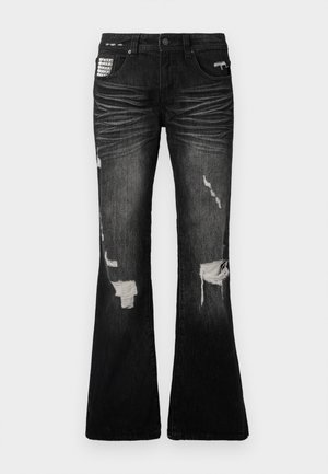 Sorte denim flare jeans med slidte lapper, frynset kant og en tætsiddende talje. Har dekorativ hardware på frontlommen.