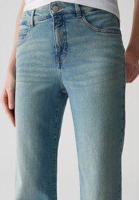 Jeans in denim azzurro chiaro con vita alta, leggeri sbiadimenti, design a cinque tasche e chiusura con bottone metallico. Tessuto liscio e vestibilità dritta.