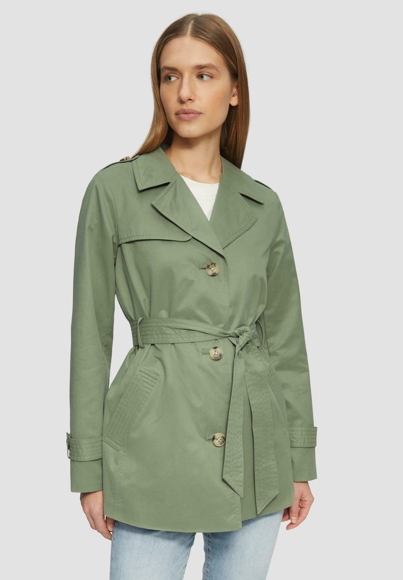 Olivovo zelený trench coat s predným zapínaním na gombíky, viazacím pásom a bočnými vreckami. Má klasický golier a kontrastné švy.