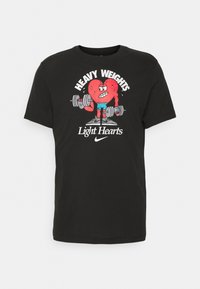 Czarny bawełniany T-shirt z grafiką czerwonego kreskówkowego serca podnoszącego ciężary z napisem "HEAVY WEIGHTS Light Hearts" oraz logo Nike.