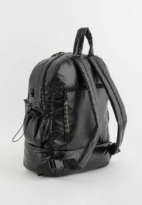 Czarny plecak z wypełnieniem, o teksturowanym wykończeniu, z dwoma regulowanymi paskami, uchwytem na górze oraz zapinaną na zamek przednią kieszenią z kolorowymi sznurkami akcentującymi.
