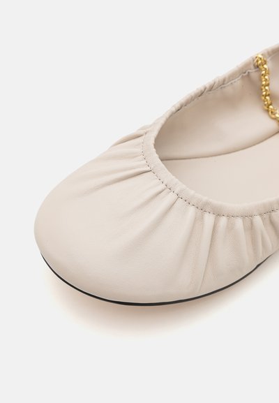 Ballerine in pelle beige con dettagli arricciati attorno all'apertura, accentuata da una decorativa catena dorata e con suola nera.