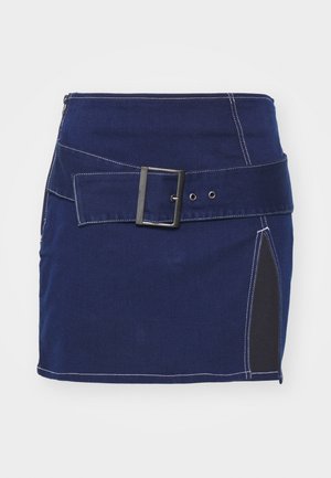Jupe en denim bleu marine avec des coutures blanches, dotée d'une large ceinture avec une boucle carrée et d'un panneau latéral en tissu noir.