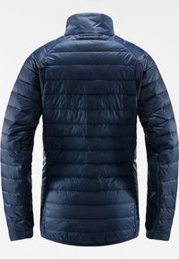 Veste matelassée légère bleu marine avec col haut et manches longues, montrée de dos sur un fond uni.