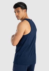 Top senza maniche di colore blu navy realizzato in miscela di cotone, con una vestibilità comoda e una texture liscia. Il retro è leggermente arcuato e privo di motivi.