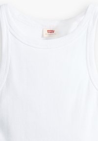 Balta ribuota maikutė su plačiu iškirpimu ir rankovėmis, su maža "Levi's" etikete arti centro. Lygus paviršius.