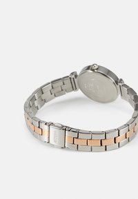 Montre en acier inoxydable argent et or rose avec un bracelet à maillons, un boîtier rond et un fermoir sécurisé. Finition lisse avec un éclat poli.