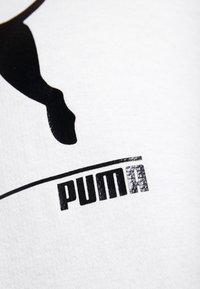 Tessuto bianco con una grande silhouette nera di un puma in salto sopra la parola "puma" in caratteri neri bold e testurizzati.