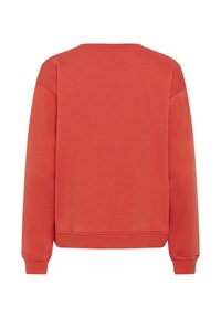 Enostavno rdeč dolg rokav crewneck pulover s rebrastimi manšetami in spodnjim delom, prikazan zadaj na beli podlagi.