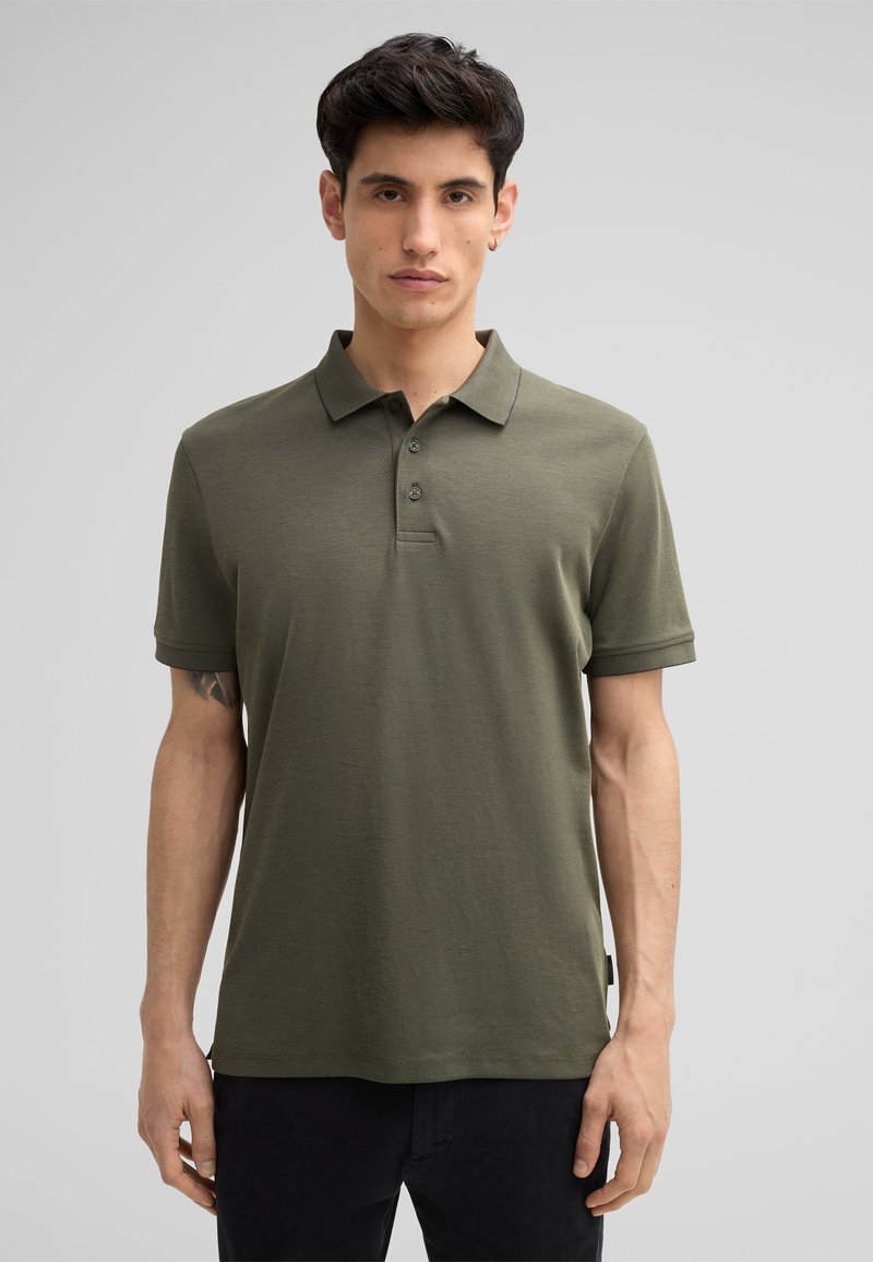 Dunkelgrünes Poloshirt aus weichem Material mit kurzen Ärmeln, drei Knöpfen und einem dezent gerippten Kragen. Sauberes, minimalistisches Design.