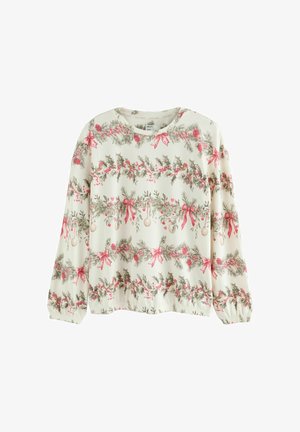 Hvid langærmet bluse med et mønster af grønne kristtjørn, røde bær og lyserøde sløjfer. Elastisk kant og manchetter tilføjer tekstur til designet.