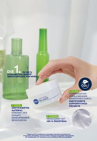 Nivea Natural Balance cream in a white container with blue text, next to two green glass bottles, against a light background.