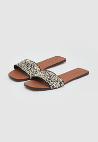 Infradito piatti con una fascia in tessuto bianco e nero a motivo e una soletta in ecopelle marrone. Presentano un design minimalista e nessun elemento metallico.