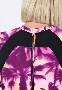 Rashguard met een levendig paars en zwart ontwerp, met palmpuntprint, een hoge hals en een rits aan de achterkant met een contrasterende trekker.