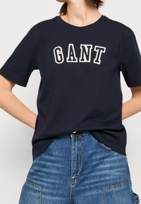 Navyblauwe katoenen T-shirt met ronde hals, korte mouwen en het "GANT" logo geborduurd in contrasterend wit. Casual pasvorm details.