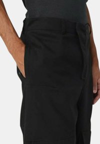  Sorte bukser med en tekstureret stof, som har sidelommer og en tætsiddende talje. Designet er enkelt og understreger funktionalitet og komfort.