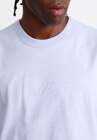 Világoskék pamut póló, amelyen diszkrét hímzett "nike" logó található a mellrészen. Kerek nyakkivágás és rövid ujjú. Simább textúra.