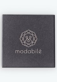 Schwarze Quadratverpackung mit einem geometrischen Logo in Roségold und dem Text "modabilé" darunter, auf einer strukturierten matten Oberfläche.