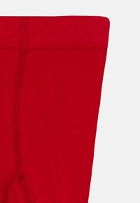 Rote Strumpfhosen aus Wolle mit einer glatten Textur und verstärkter Zehenpartie. Der Bund ist elastisch für einen bequemen Sitz und Tragekomfort.