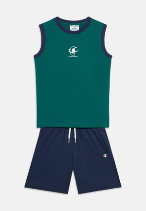 Chemise verte sans manches avec un bord bleu marine et un logo sur la poitrine, associée à un short bleu marine doté d'une ceinture élastique et de poches latérales.
