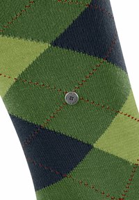 Kniestrumpf mit einem grün-blauen Argyle-Muster, das rot genähte Akzente und ein silbernes, rundes Logo in der Mitte aufweist. Hergestellt aus strukturiertem Stoff.