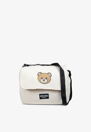 Borsa a tracolla in canvas beige con un design di faccia d'orso sulla patta; presenta una tracolla nera regolabile e un'etichetta con logo Moschino Baby.