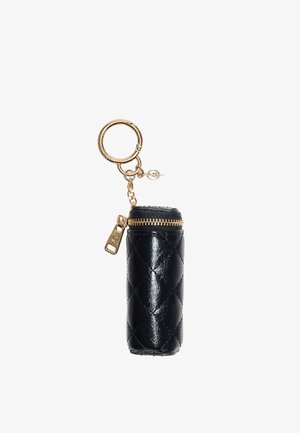 Porte-clés cylindrique en cuir matelassé noir avec fermeture éclair dorée et anneau porte-clés doré fixé par une petite chaîne.