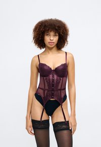 Burgunder satin- und spitzen Mieder mit transparenten Einsätzen, vorderen Knöpfen, verstellbaren Trägern und Halterungen für Strümpfe. Schwarze halterlose Strümpfe.