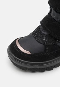 Botte d'hiver noire avec des bandes Velcro, dotée d'un dessus en nylon lisse et d'une zone de orteil en daim, rehaussée de détails scintillants et d'une semelle texturée.