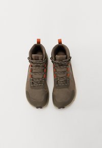 Brune høye sneakers med mesh tekstur, oransje aksenter og tykke snørebånd. Inkluderer en trekktabbe bak for enkel påkledning.