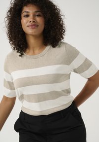 Beige en witte gestreepte korte mouwen gebreide top met een ronde halslijn, zachte textuur en een ontspannen fit, gecombineerd met donkere broeken.