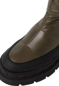 Botín de invierno acolchado en verde oliva con suela de goma negra, que presenta secciones cosidas y una textura suave y brillante en la parte superior.