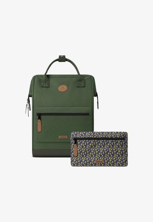 Dark green fabric backpack with a textured finish, featuring a front zip pocket and a smaller floral-patterned pouch in blue and yellow.