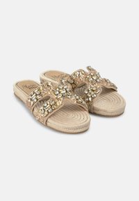 Beige slide sandals with multi-colored gemstone embellishments on straps, a jute rope-like sole, and a textured footbed.