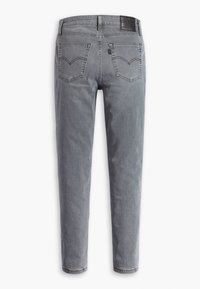 Jeans de mezclilla gris con un diseño de pierna recta, que cuentan con dos bolsillos traseros y un parche de cuero en la cinturilla. Textura suave, desgaste mínimo.