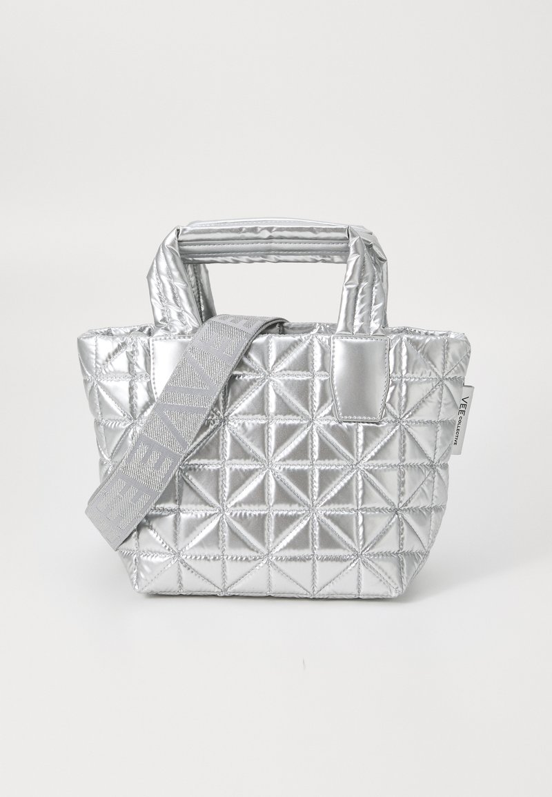 Srebrna pikowana torba o geometrycznym wzorze, z podwójnymi uchwytami i odpinanym paskiem z logo. Wykonana z tkaniny metalicznej.