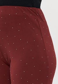 Bordeaux leggings med en slät textur, med silverstift jämnt fördelade över tyget. Elastisk midja för en åtsittande design.
