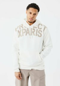 Sudadera blanca con "PROJECT XPARS" en grandes letras beige, con un bolsillo tipo canguro y puños de canalé. Textura suave, ajuste relajado.