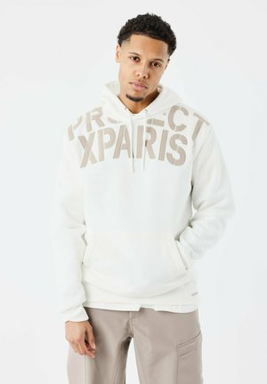 Sudadera blanca con "PROJECT XPARS" en grandes letras beige, con un bolsillo tipo canguro y puños de canalé. Textura suave, ajuste relajado.