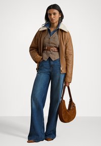 Brun läderjacka med ett fårskinnskrage, rutigt väst, vida blå jeans och en brun mockaväska. Enkla accessoarer fulländar looken.